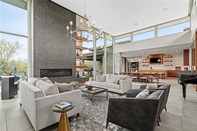 living room featuring a fireplace, a towering ceiling, a chandelier, and plenty of natural light