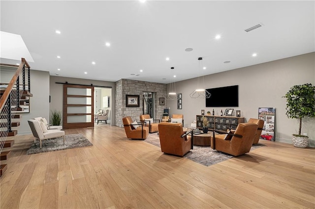 living room with a barn door and light hardwood / wood-style floors