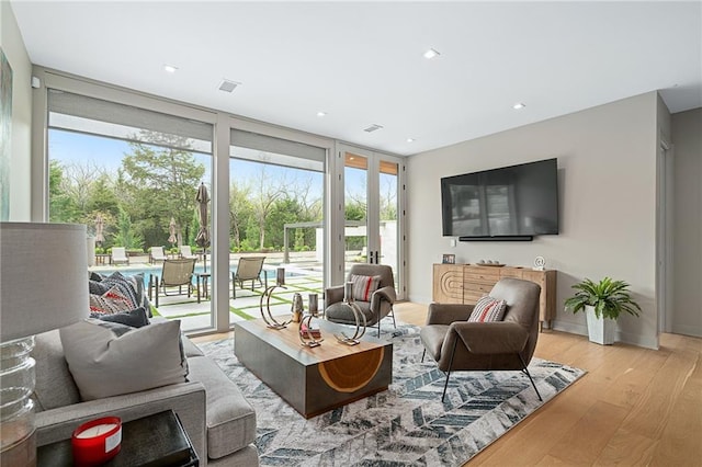 living room with light hardwood / wood-style floors and a wall of windows