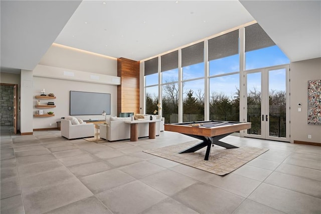 unfurnished living room with light tile patterned flooring, a healthy amount of sunlight, a wall of windows, and billiards