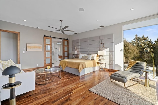 bedroom featuring wood-type flooring, a barn door, and access to outside