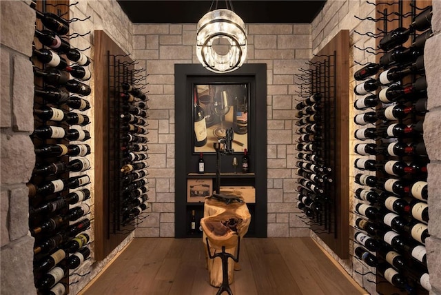 wine room with an inviting chandelier and hardwood / wood-style floors