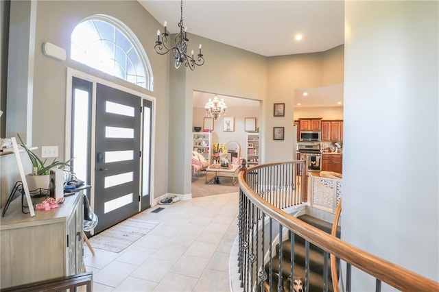 foyer entrance featuring light tile patterned flooring, a chandelier, and a high ceiling