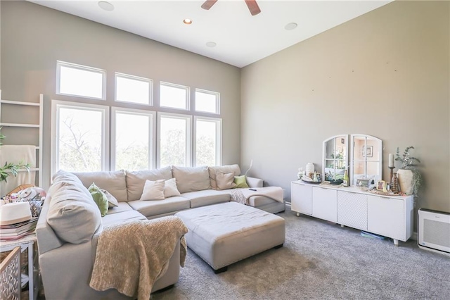 living room featuring ceiling fan, carpet, and a high ceiling