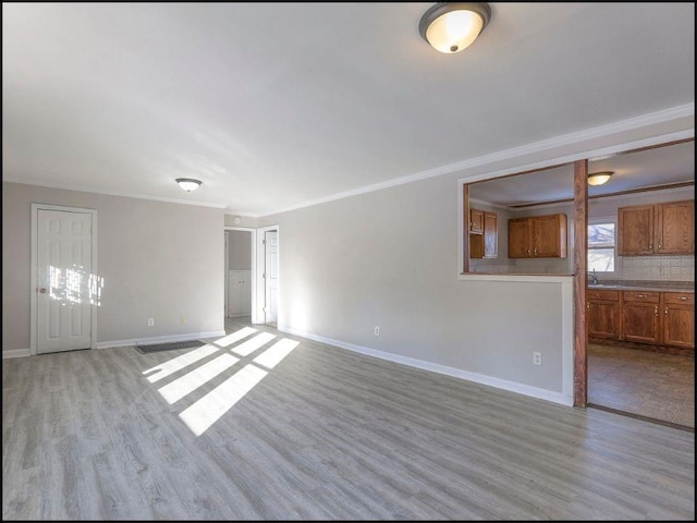 unfurnished living room featuring crown molding and light hardwood / wood-style flooring