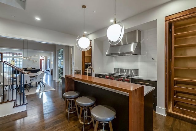 kitchen featuring dark hardwood / wood-style flooring, decorative light fixtures, and an island with sink