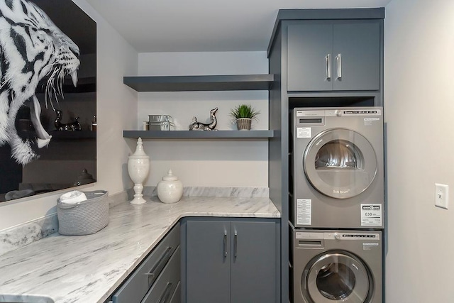 laundry area featuring stacked washing maching and dryer and cabinets