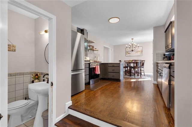 interior space featuring dark hardwood / wood-style flooring, gray cabinetry, appliances with stainless steel finishes, and an inviting chandelier