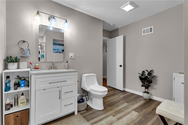 bathroom with hardwood / wood-style flooring, vanity, and toilet