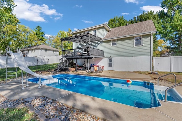 view of swimming pool featuring a water slide, a wooden deck, and a patio