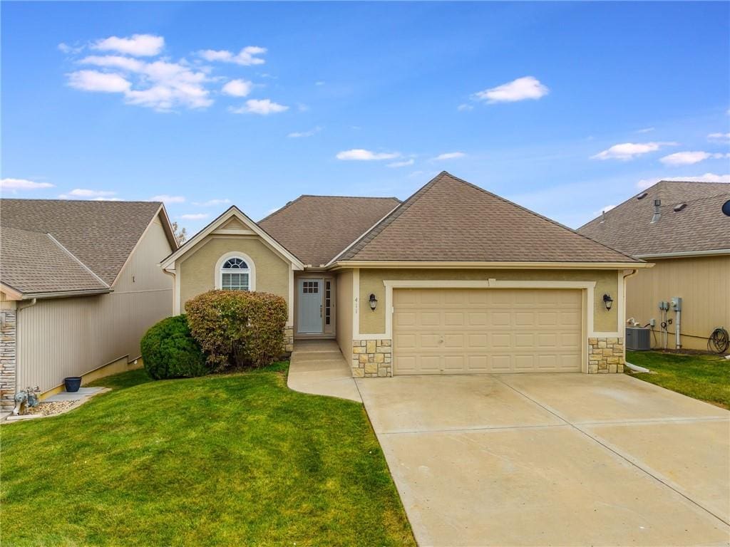 view of front of home with cooling unit, a front yard, and a garage