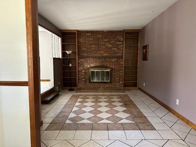 unfurnished living room with a textured ceiling, built in features, a fireplace, and light tile patterned floors