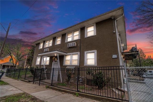 5121 Thompson Ave, Kansas City, MO 64124 - multi unit property featuring a fenced front yard, a wall mounted air conditioner, and stucco siding