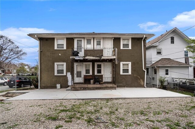 5121 Thompson Ave, Kansas City, MO 64124 - back of property with fence, a balcony, and stucco siding