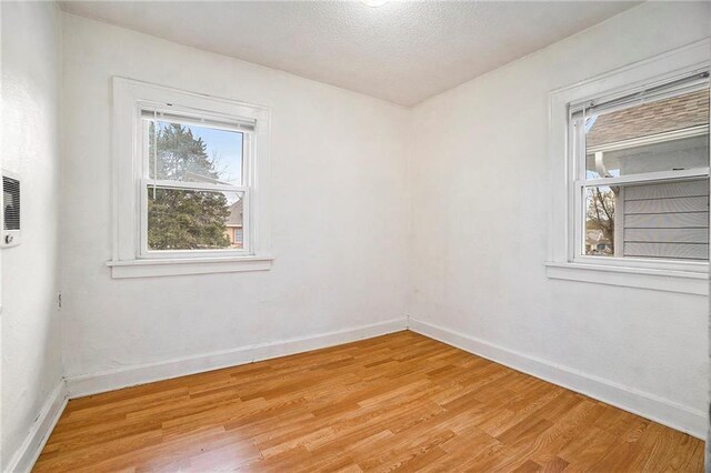 5121 Thompson Ave, Kansas City, MO 64124 - empty room featuring light wood-style floors, a textured ceiling, and baseboards