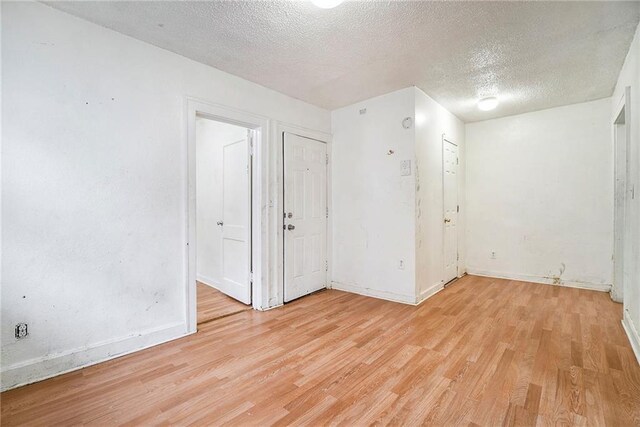 5121 Thompson Ave, Kansas City, MO 64124 - spare room with baseboards, a textured ceiling, and light wood-style flooring