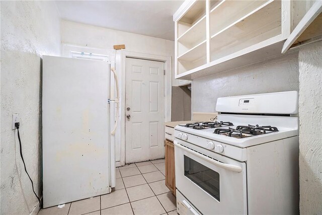 5121 Thompson Ave, Kansas City, MO 64124 - kitchen with light tile patterned floors, light countertops, and white appliances