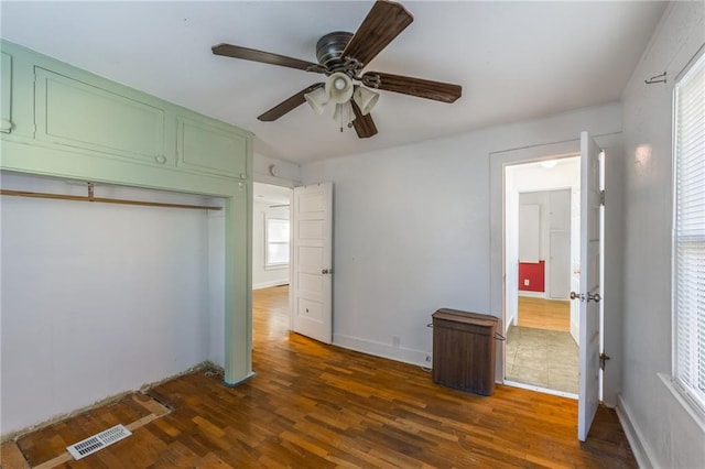 unfurnished bedroom with a closet, dark hardwood / wood-style floors, and ceiling fan