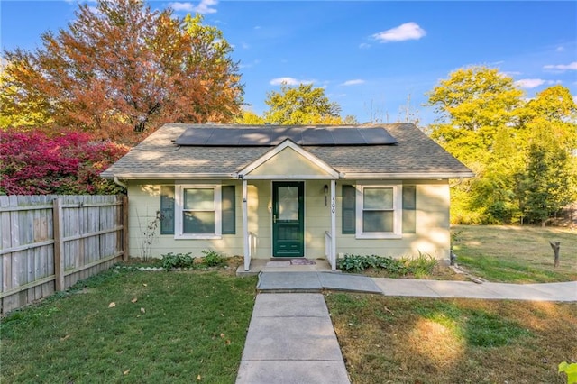 bungalow-style house with covered porch, a front lawn, and solar panels