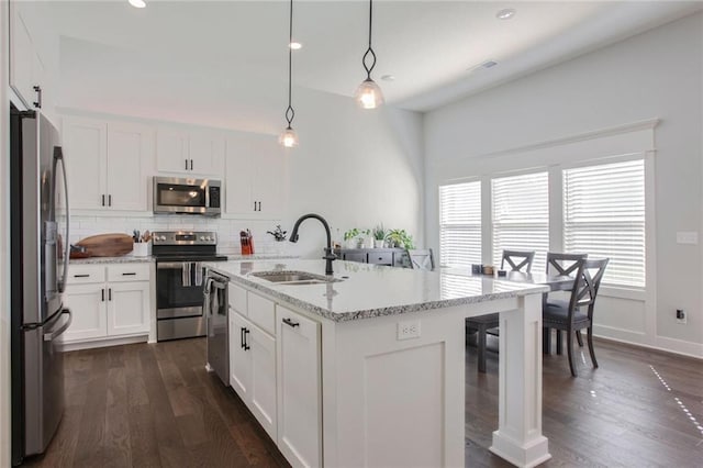 kitchen with white cabinetry, stainless steel appliances, an island with sink, and hanging light fixtures