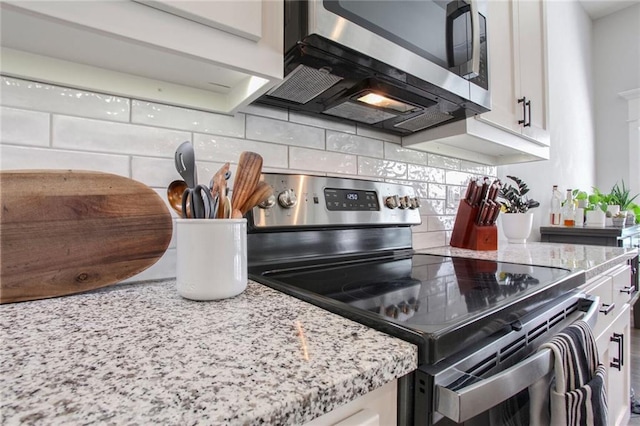 kitchen featuring appliances with stainless steel finishes, light stone counters, white cabinets, and tasteful backsplash