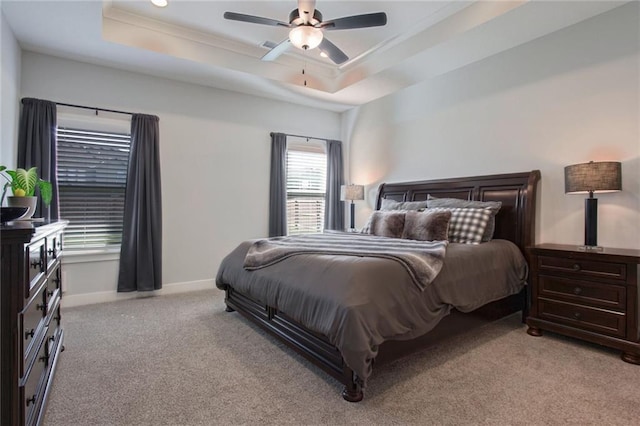 carpeted bedroom featuring ceiling fan, a raised ceiling, and crown molding