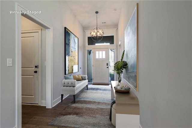 entryway with an inviting chandelier and dark wood-type flooring