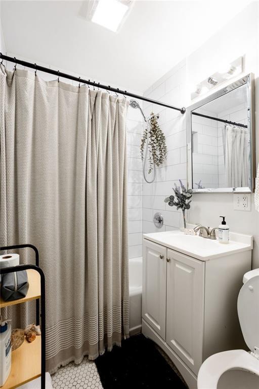 full bathroom featuring toilet, shower / bath combination with curtain, and vanity