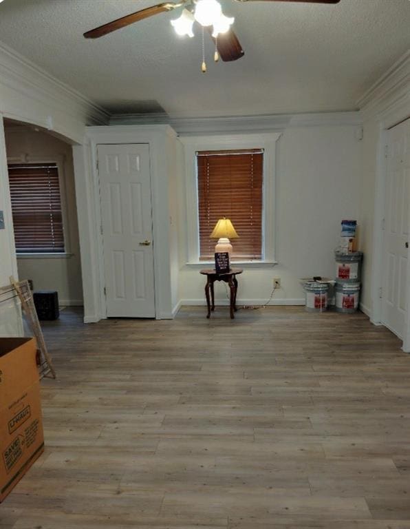 interior space with a textured ceiling, light hardwood / wood-style flooring, ceiling fan, and ornamental molding