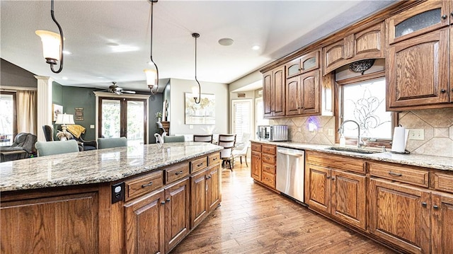 kitchen with sink, stainless steel dishwasher, hanging light fixtures, and a kitchen island