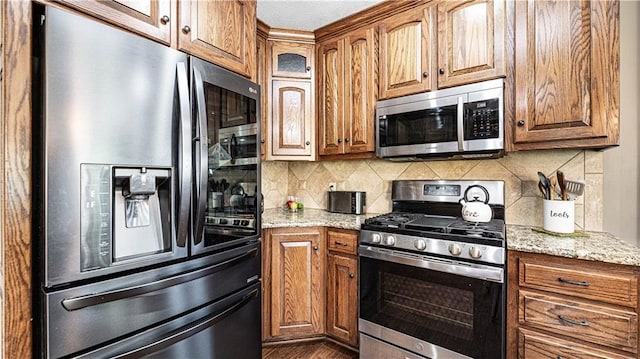 kitchen featuring light stone counters, stainless steel appliances, and backsplash