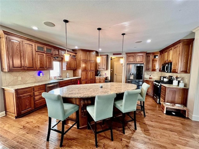 kitchen featuring pendant lighting, sink, a kitchen island, and appliances with stainless steel finishes