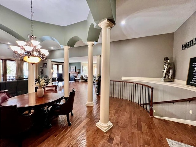 dining room featuring decorative columns, hardwood / wood-style flooring, and an inviting chandelier