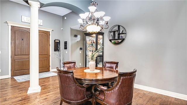 dining room with wood-type flooring, a chandelier, and ornate columns