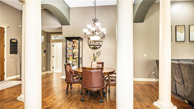 dining space featuring hardwood / wood-style flooring, decorative columns, and a notable chandelier