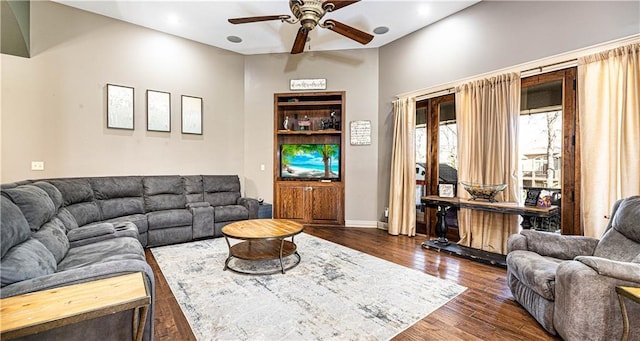 living room featuring dark wood-type flooring and ceiling fan