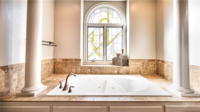 bathroom with tiled tub and ornate columns