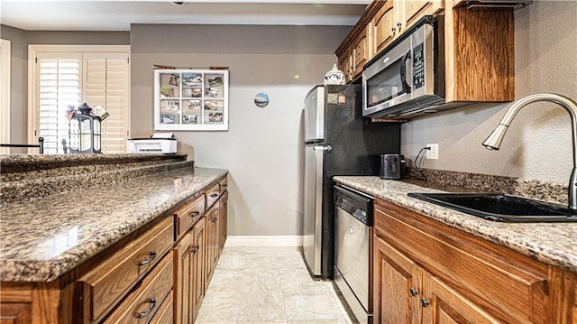 kitchen featuring sink, stainless steel appliances, and dark stone counters