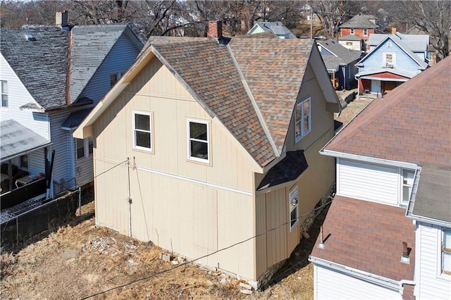 view of property exterior featuring a shingled roof and fence