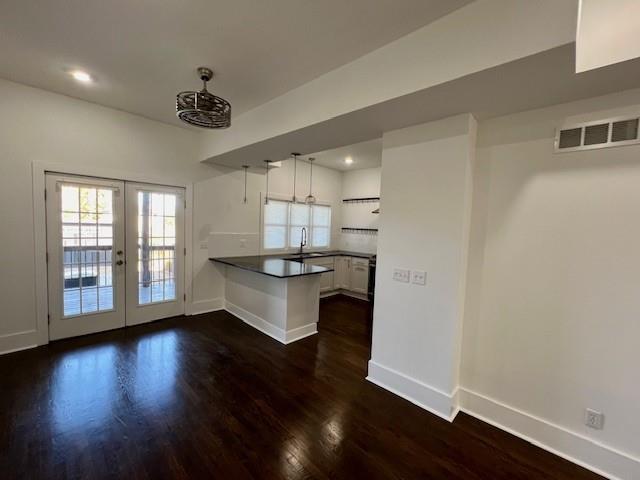 kitchen featuring pendant lighting, dark wood-type flooring, french doors, kitchen peninsula, and white cabinetry