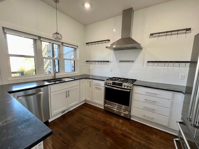 kitchen with white cabinets, sink, wall chimney exhaust hood, decorative light fixtures, and stainless steel appliances