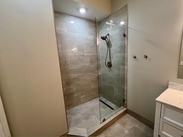 bathroom featuring tile patterned flooring, vanity, and a tile shower