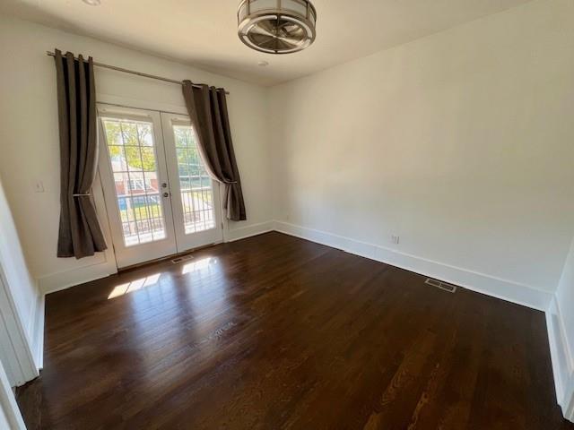 empty room featuring french doors and dark hardwood / wood-style flooring