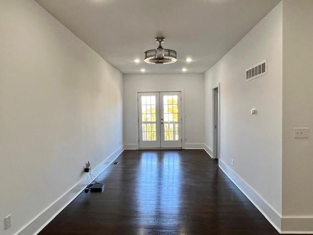 empty room featuring french doors and dark wood-type flooring