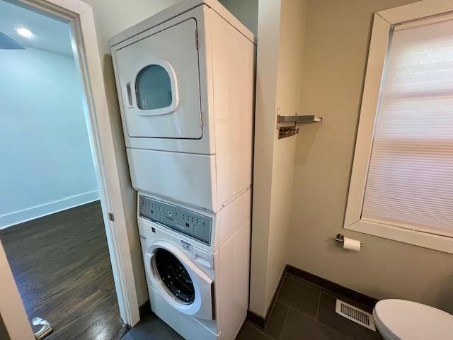 laundry room featuring stacked washer / dryer and dark hardwood / wood-style floors