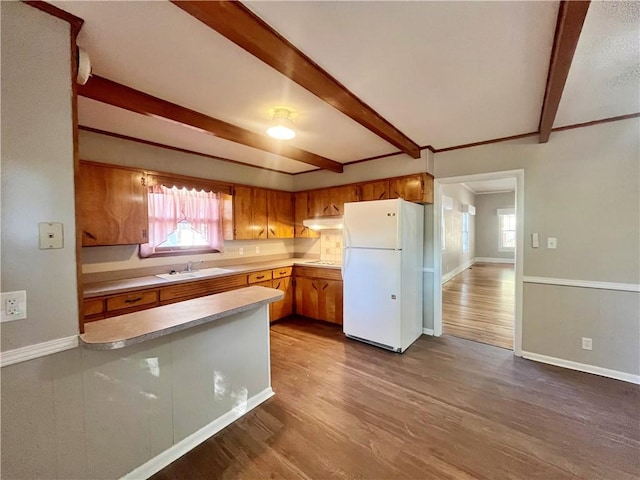 kitchen with beamed ceiling, sink, hardwood / wood-style flooring, and white refrigerator