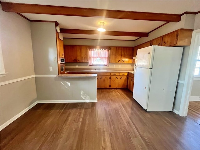 kitchen featuring dark hardwood / wood-style floors, beam ceiling, kitchen peninsula, sink, and white fridge