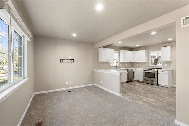 kitchen featuring baseboards, light countertops, recessed lighting, appliances with stainless steel finishes, and a sink