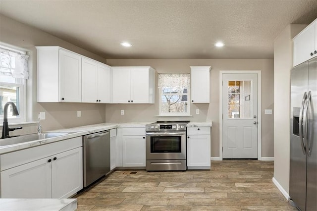 kitchen with white cabinets, appliances with stainless steel finishes, light countertops, and a sink