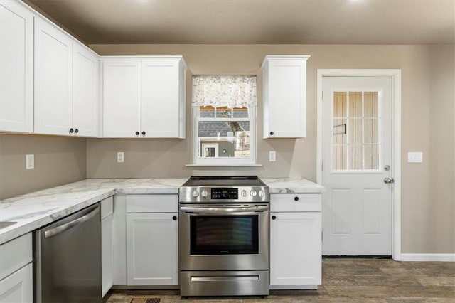 kitchen featuring baseboards, light stone countertops, stainless steel appliances, wood finished floors, and white cabinetry